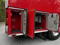 The rear compartment doors of a red 1991 Sutphen Deluge fire truck are open revealing storage space and equipment compartments inside
