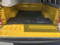 The bed of a 2015 RAM 1500 truck is shown with a yellow interior featuring a textured rubber mat and no visible cargo