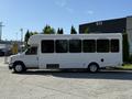 A white 2021 Ford Econoline shuttle bus with large windows and a high roof parked on a concrete surface