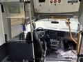 Interior view of a 2020 Chevrolet Express showing the driver's seat dashboard and controls with an open area for passenger access