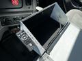 An open metal compartment with a black interior and a remote control labeled Stealth resting on the edge