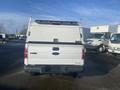 White 2013 Ford F-150 with a cap on the bed viewed from the rear