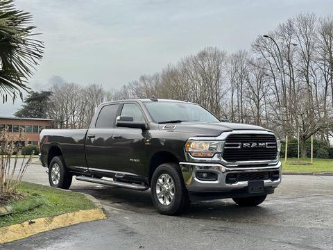 A gray 2020 RAM 3500 pickup truck with a chrome grille and polished wheels parked on a paved surface showcasing its muscular build and sleek design