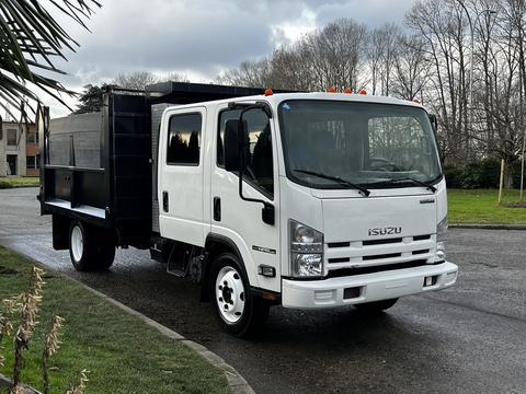 A white 2015 Isuzu NPR HD truck with a black cargo bed and cab showing a sleek front design and visible headlights