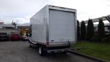 A 2018 Ford Transit box truck with a large white cargo area and a rear loading door parked in a lot