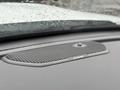 A close-up of a dashboard speaker grille in a 2024 RAM 5500 featuring a carbon fiber design and a small control button