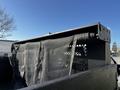 A close-up view of the bed of a 2018 Ford F-550 with a black tarp partially covering the cargo area and a lattice panel visible