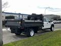 A 2021 Ford F-550 truck with a flatbed and tool storage compartment in the back, featuring a white cab and black flatbed