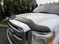 A 2013 Ford F-350 SD with a shiny chrome grille and a black hood protector on the front edge of the hood