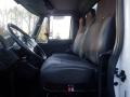 Interior view of a 2014 International Durastar truck showing the driver’s seat and two passenger seats with black fabric upholstery