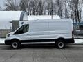 A 2021 Ford Transit van in white with black accents parked on a street featuring a cargo area and large side door