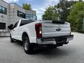 A white 2017 Ford F-250 Super Duty truck viewed from the rear showing its bed tailgate and chrome accents
