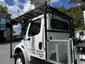 A 2012 Freightliner M2 106 truck with a metal cage and a bucket lift attached on the rear side displaying weight specifications on the door