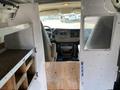 Interior view of a 2012 GMC Savana showing the driver's seat dashboard and wooden shelves installed on the sides of the van