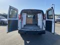 2012 GMC Savana van with open double doors revealing a spacious interior featuring shelves and a smooth floor for storage