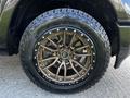 Close-up of a 2019 RAM 1500 tire and wheel featuring an intricate bronze alloy rim with multiple spokes and a rugged all-terrain tire design