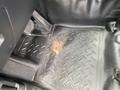 The floor mat of a 2021 Ford Explorer showing a worn area with a small piece of metal visible on a textured rubber surface