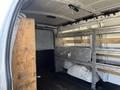Interior of a 2016 GMC Savana cargo van featuring wooden and metal shelving on the sides and an empty floor space
