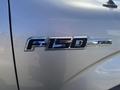 Close-up of a metallic badge on a 2014 Ford F-150 displaying the model name F-150 and FX4 trim designation
