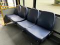 A row of three blue fabric seats inside a vehicle designed for public transportation