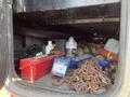 A storage compartment of a 2009 Peterbilt Highway filled with tools including a red toolbox chains and various bottles and equipment