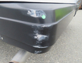 Close-up of the rear bumper of a 2020 Chevrolet Express showing scratches and scuff marks on a black surface