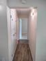 Interior hallway of a 2BHK apartment with doors on both sides and a light fixture illuminating the space