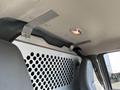 Interior view of a 2014 Chevrolet Express showing metal brackets mounted to the ceiling and a partition with perforated design separating the front and rear spaces