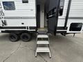 A 2022 Keystone Hideout RDWE 20RDWE travel trailer with a set of stairs leading to the entry door and a black railing on the side