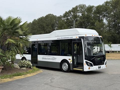 A 2018 Grande West Vicinity bus in white and black with a sleek design and open doors inviting passengers inside