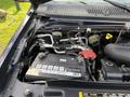 A close-up view of a 2011 Ford Econoline engine compartment showing the battery and various engine components such as hoses and caps