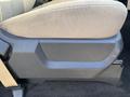 A close-up of the fabric seat cushion of a 2014 Ford F-350 SD showing beige upholstery and a plastic side panel with scratches and scuff marks