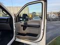 A white 2018 Ford F-350 truck with an open driver's side door showcasing the interior panel and armrest