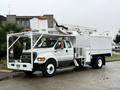 A white 2015 Ford F750 utility truck with an elevated aerial lift and equipment compartments attached to the side