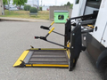 A 2020 Chevrolet Express van with a wheelchair lift extended, featuring a yellow platform and black safety bars