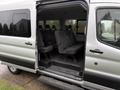 A 2019 Ford Transit van with an open side door revealing multiple rows of seating inside