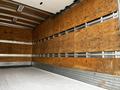 A 2022 Isuzu NPR box truck with a wooden interior, featuring large plywood panels along the walls and a flat, white floor