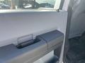 A 2015 Ford F-450 SD door handle and interior panel are visible showcasing a gray surface with a textured grip and a standard door release latch