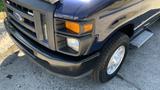 A blue 2013 Ford Econoline van with a black front bumper and chrome grille showing the Ford logo and one visible headlight