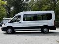 A white 2022 Ford Transit van with black accents visible from the side showcasing its large windows and spacious passenger area
