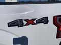 A close-up of a 4x4 badge on a white 2019 Ford F-150 truck