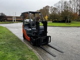 A 2017 Toyota 8FCGCU25 forklift with a black and orange design parked on a pathway with its forks lowered