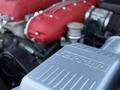 Close-up of a 2005 Ferrari 612 Scaglietti engine showcasing the red intake manifold and silver engine cover with the Ferrari logo