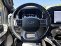 Steering wheel of a 2021 Ford F-150 with control buttons and a digital dashboard display behind it
