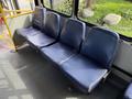A row of blue fabric bus seats with sturdy armrests arranged in a line