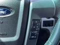 Close-up of the steering wheel control panel of a 2014 Ford F-150 featuring buttons for volume media playback and a confirmation button