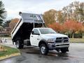 A white 2012 Dodge Ram 5500 with a raised dump bed positioned at an angle showcasing its cargo area