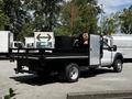 A white 2016 Ford F-550 with a flatbed and tool storage on the back featuring a skull decoration and a red warning flag attached