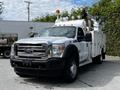 A 2016 Ford F-550 truck with a white body and a utility bed equipped with a bucket lift and various lights on top