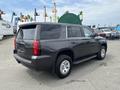 A 2016 Chevrolet Tahoe in dark gray with chrome accents and off-road tires parked at an industrial site